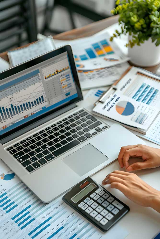 bookkeeping services miami workspace showing financial reports, accounting charts, calculator, and laptop used for professional bookkeeping tasks