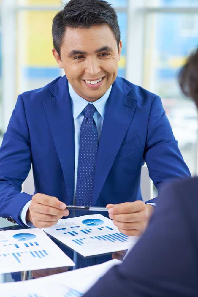 cpa-pompano-beach-3 Smiling accountant discussing financial reports with a client at an office desk, providing professional cpa pompano beach services
