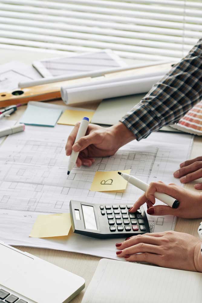 miami-fl-tax-planning Professionals calculating costs and reviewing plans with calculator and drawings as part of miami tax planning process