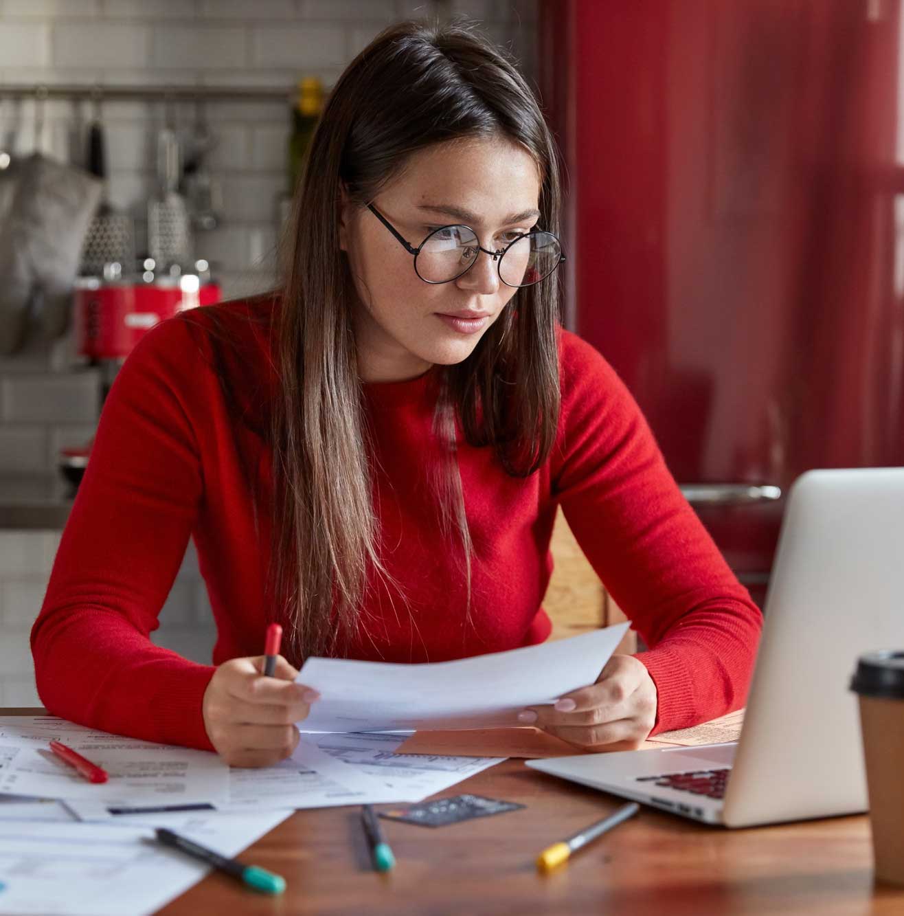 tab-pre-4 Woman reviewing financial documents at a desk with a laptop, calculator, and paperwork, focused on budgeting and filing taxes at home, Tax Preparation Miami